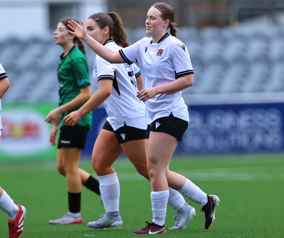 Untitled design (3) Two female football players running for the ball during a soccer match looking determined